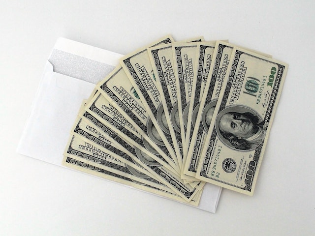 fanned out paper money sitting on a white envelope 